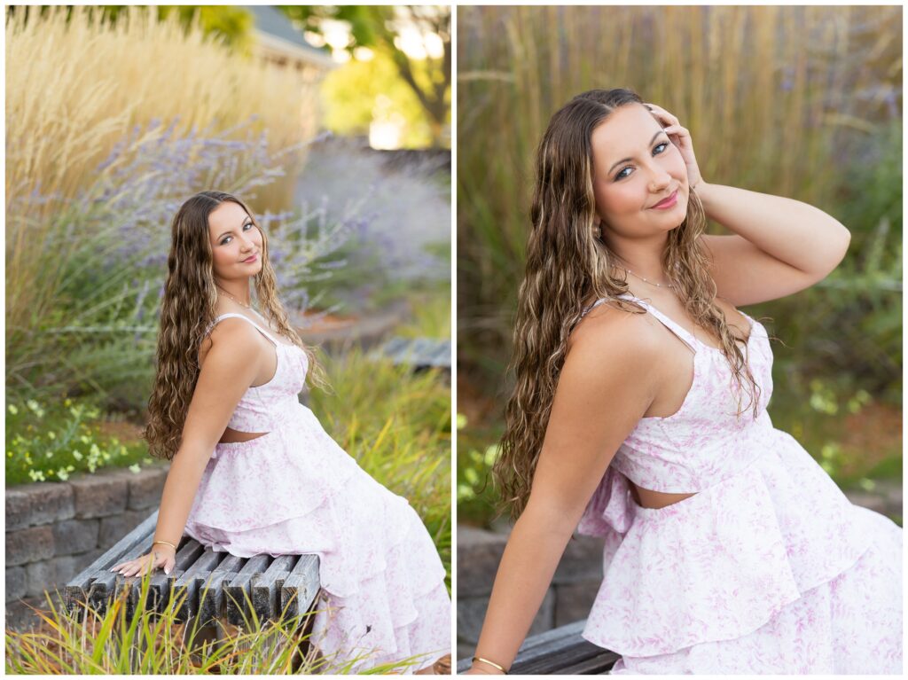 A young woman in a light pink floral dress sits on a bench in a garden, surrounded by tall grass and purple flowers. She smiles softly, conveying a serene and confident mood.
