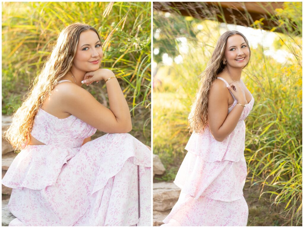 A woman with long hair wearing a tiered pink dress poses outdoors among green plants. She smiles softly, exuding a calm and joyful vibe.