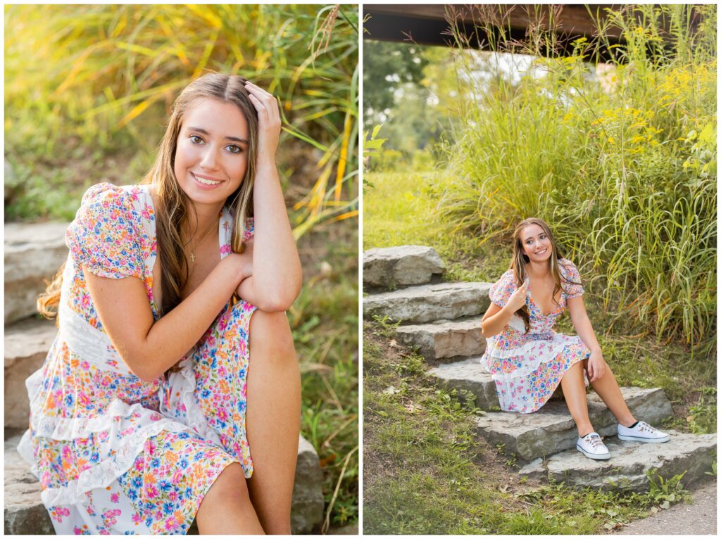 Teenage girl in a floral dress sits on stone steps surrounded by tall grass. She smiles gently, exuding a warm, carefree vibe.