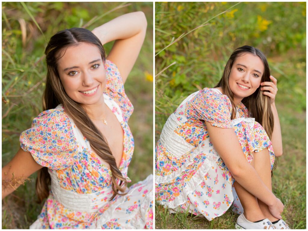 Young woman in a floral dress sits on grass, smiling warmly. Her long hair is styled neatly, surrounded by lush greenery, conveying a serene mood.